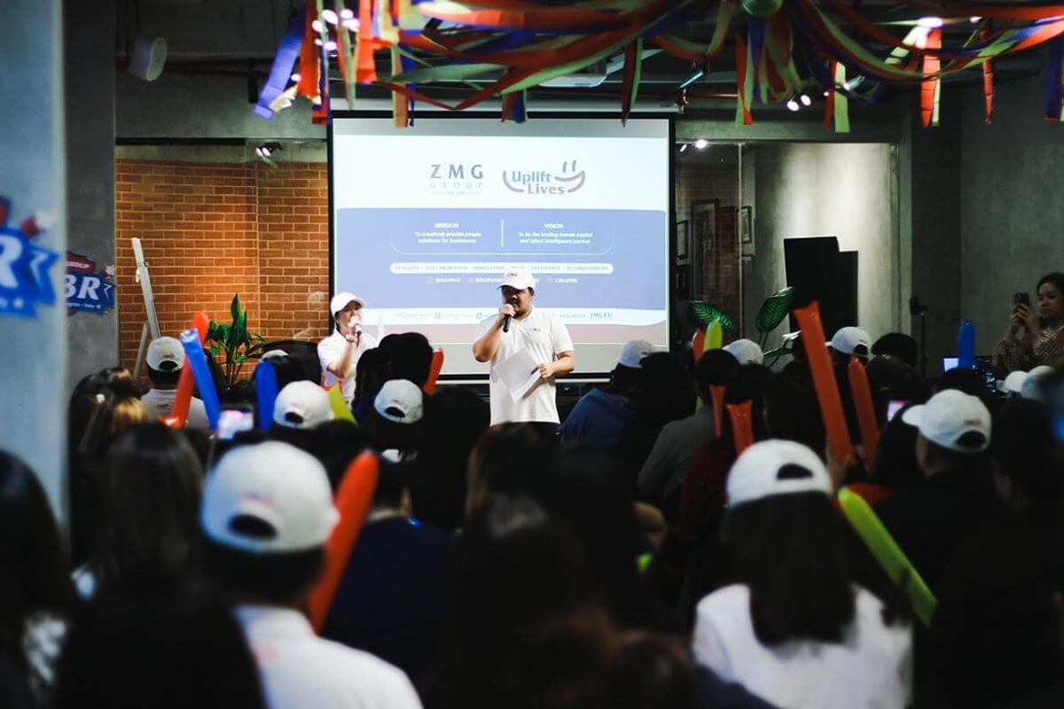 Employe speaking on stage during a company event with an audience holding inflatable cheering sticks