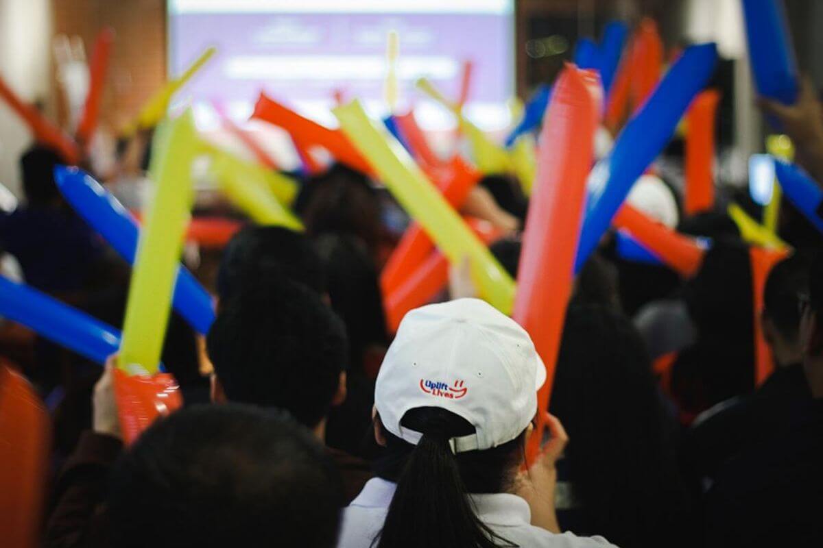 Employees posing together in front of a presentation screen at a company event